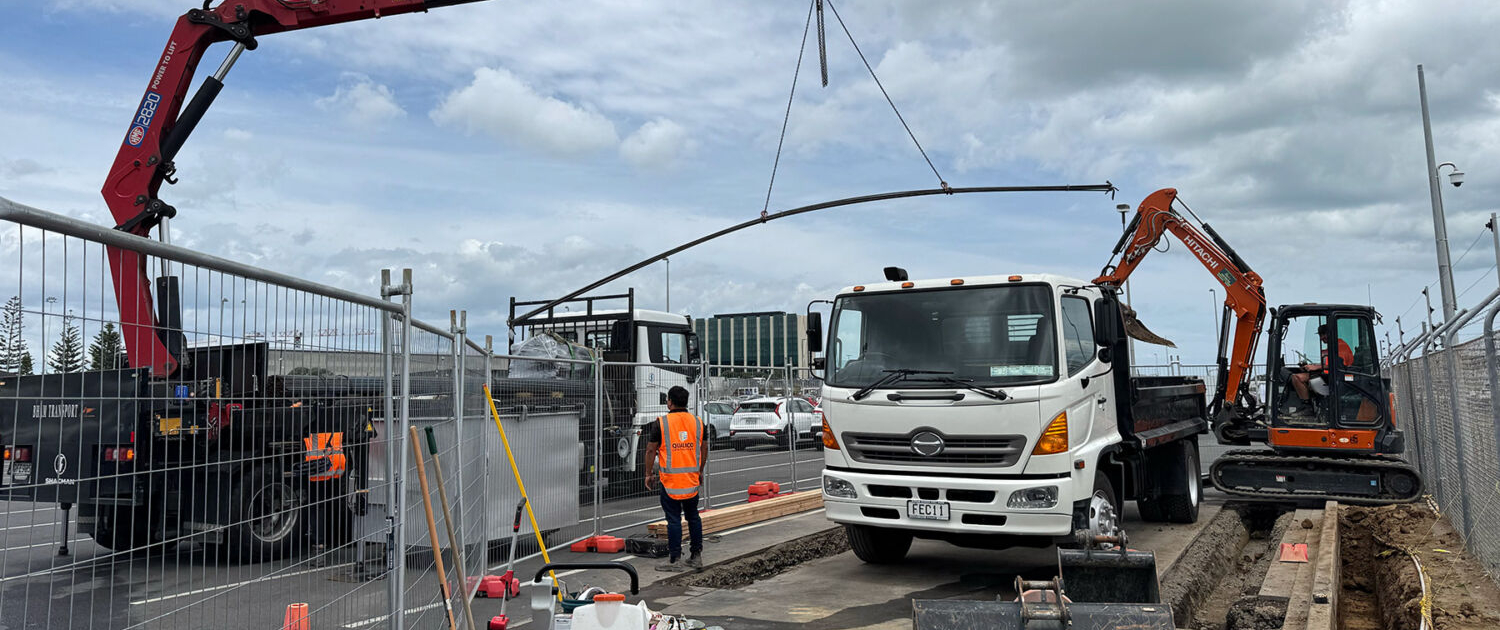 image of a crane lifting a pipe from a truck